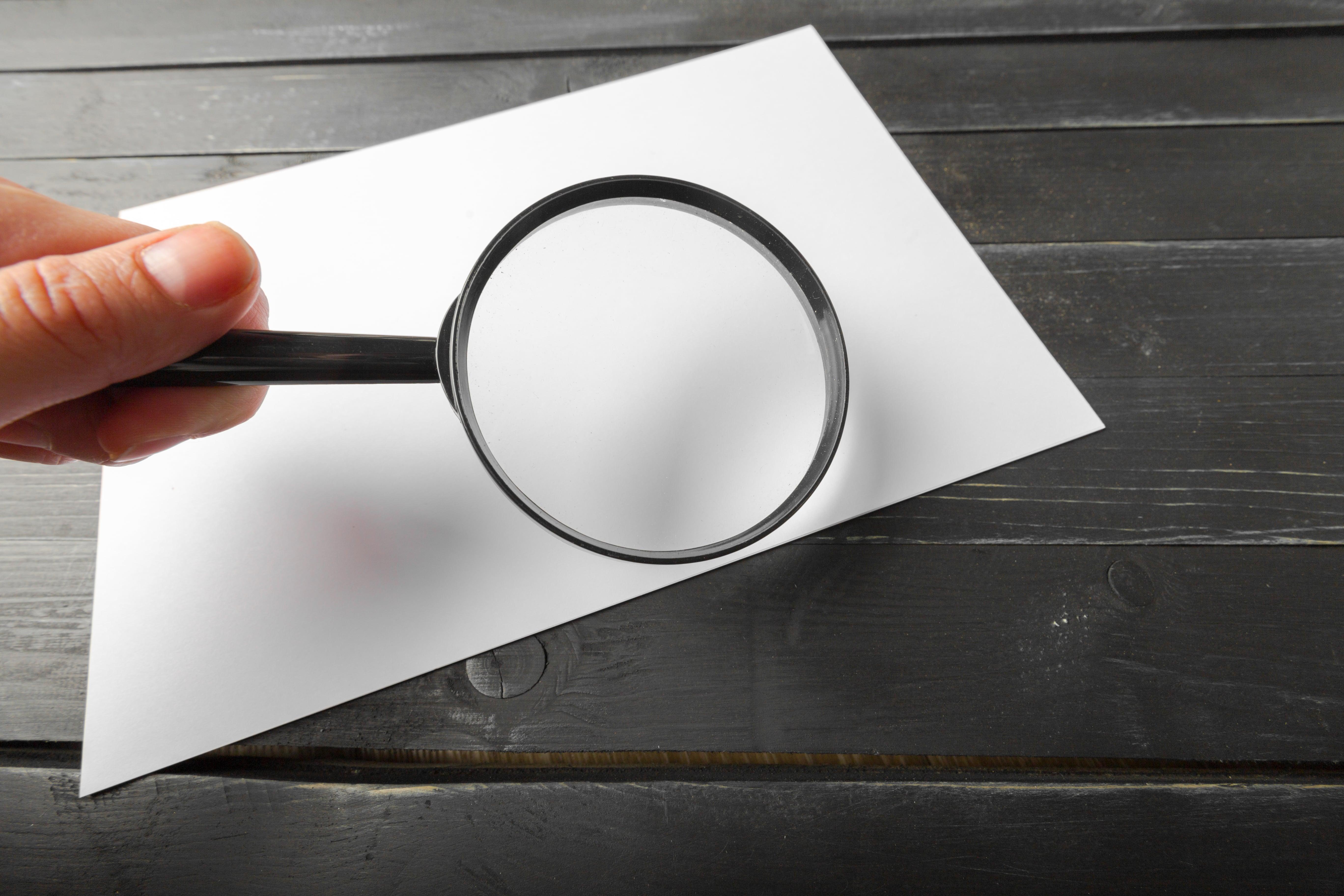 Magnifying glass blank paper wooden table min